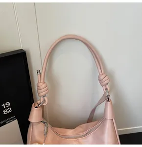 Close-up of pink crescent tote bag with knotted strap detail and silver metal buckle