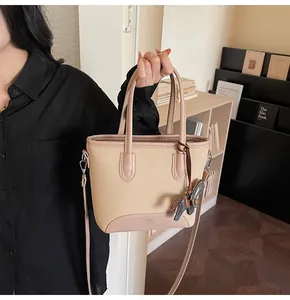 Detalle del bolso de lona beige y cuero PU rosa con un colgante decorativo de caballo