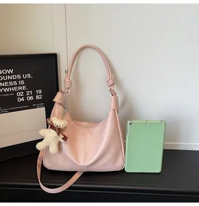 Detail of pink faux leather hobo bag with a cute teddy bear charm and knot handle