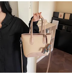 Detalle del bolso tote de lona beige con ribete de cuero rosa y colgante de caballo