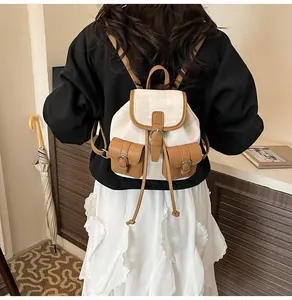 Vista detallada de una mini mochila de lona con adornos de cuero usada por modelo en el hogar