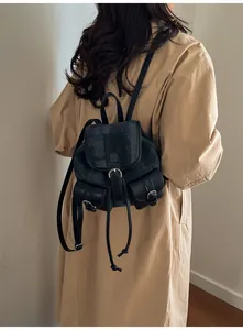 Primer plano de una mochila retro de mezclilla y cuero negro sobre una gabardina