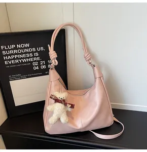 Close-up of pink hobo bag with knotted strap detail and cute plush bear keychain
