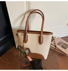 Detalle del bolso de lona con adornos de cuero y colgante decorativo de caballo