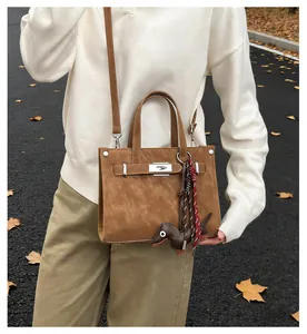 Detail of tan leather handbag with metal turn-lock and cute dachshund dog charm