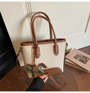 Detalle del bolso de lona vintage con ribetes de cuero y colgante decorativo