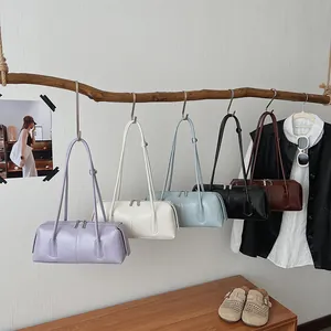 Minimalist baguette shoulder bags in five colors on a wooden display stand