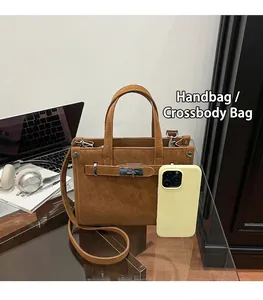 Detailed close-up of brown leather handbag with metal turn-lock and adjustable strap
