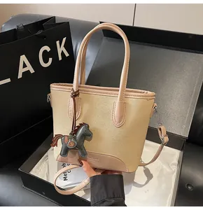 Detalle de bolso saco de lona con ribete de cuero junto a caja de regalo y bolsa de compra