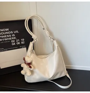 Detail of creamy white leather hobo bag with knotted strap and cute bear charm