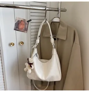 Detail of cream oversized tote bag with knot strap and plush bear charm on hanger