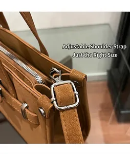 Close-up of silver metal buckle and adjustable shoulder strap on brown leather handbag