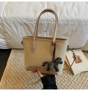 Detalle del bolso saco de lona con colgante de poni de cuero marrón y logo impreso
