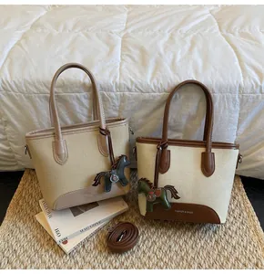 Detalle de bolsos tipo cubo de lona con acabados en cuero y colgante de caballo