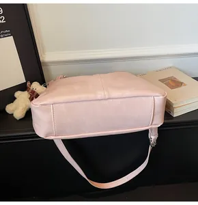 Detail of pink PU leather tote base and side with cute plush bear charm accessory