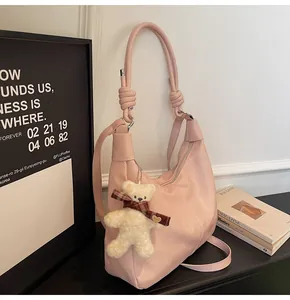 Detail of pink hobo shoulder bag with leather texture and cute bear charm pendant
