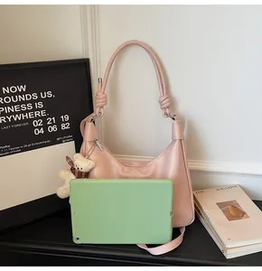 Pink matte leather hobo bag with knot straps and bear charm shown with tablet size guide