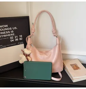 Pink crescent hobo bag detail with knotted strap, bear charm and tablet inside for size