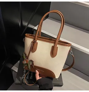 Primer plano del bolso cubo de lona con ribete de cuero y un colgante de caballo decorativo