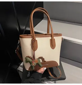 Detalle del bolso de lona con adornos de cuero y colgante decorativo de caballo verde
