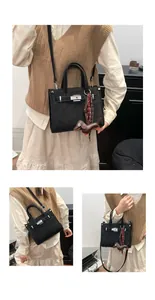 Close-up of black matte shoulder bag with silver hardware and a cute dog charm