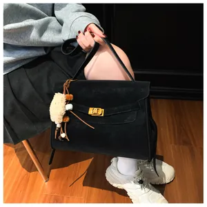 Detailed view of a black matte tote bag with gold buckle and plush charm on a model