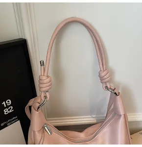 Close-up of pink shoulder bag showing knotted rope strap and silver metal zipper detail