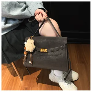 Detail of dark brown matte tote bag featuring gold buckle closure and cute bear charm