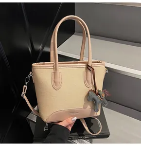 Detalle del bolso tipo cubo de lona con ribete de cuero y colgante de pony