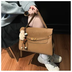 Detail of brown vintage frosted shoulder bag with gold twist lock and bear charm