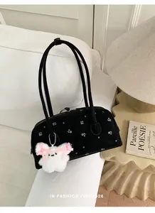 Detail van bloemen onderarmtas met zwarte suède textuur en konijnen knuffelhanger