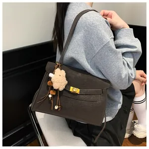 Detail of dark brown matte suede shoulder bag with gold twist lock and bear charm