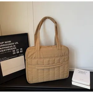 Detalle del bolso tote acolchado caqui con costuras verticales y compartimento para portátil