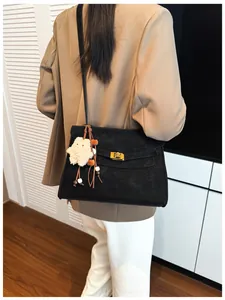 Detail of black suede tote bag with gold twist lock and white plush star charm