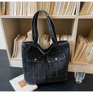Detail of vintage grey denim tote bag with functional front pockets and metal buckles