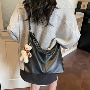 Minimalist black faux leather tote bag with knot shoulder strap and teddy bear charm