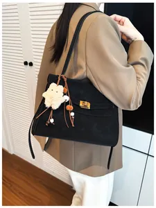 Detail view of black matte underarm tote bag with gold twist lock and plush bear charm