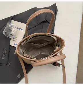 Vista superior de un bolso saco beige que muestra el interior espacioso y el bolsillo de cremallera