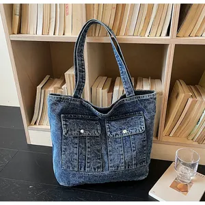Detailed close-up of dark blue vintage denim tote bag featuring utility pockets and metal snaps