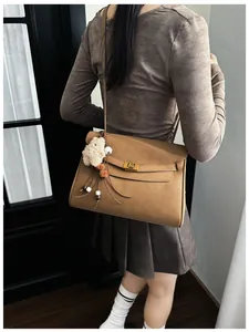 Detail of camel matte tote bag with golden twist lock and plush charm accessory