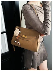 Detail of vintage brown suede tote bag featuring a gold clasp and cute bear charm