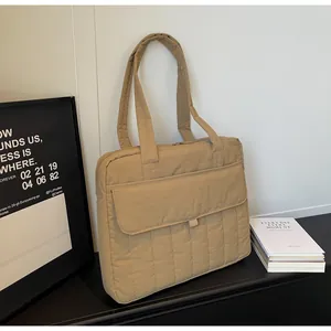 Vista detallada del bolso acolchado para portátil en caqui con costuras y bolsillo frontal