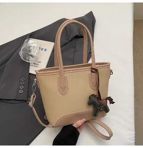 Detalle del bolso de lona con adornos de cuero y colgante decorativo de caballo