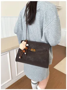 Detail of vintage matte crossbody bag with gold lock hardware and plush bear charm