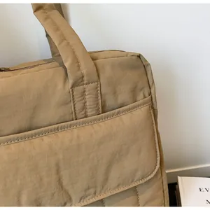 Detalle del bolso tote de nailon caqui con cremallera metálica y costuras reforzadas