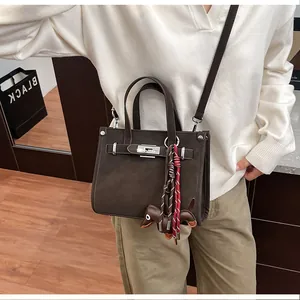 Detailed close-up of dark brown leather handbag with silver twist lock and puppy charm