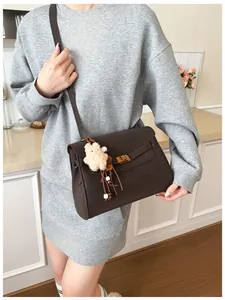 Detail of dark brown pebble leather shoulder bag with gold turn-lock and teddy bear charm