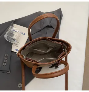 Vista superior de bolso tipo cubo marrón con cierre de cremallera y diseño interior