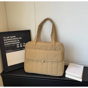 Detalle de bolso tote acolchado caqui con costuras verticales y bolsillo frontal grande