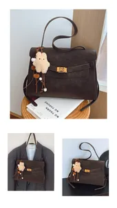 Detail view of coffee suede shoulder bag with gold twist lock and cute bear charm